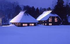 雪の積もったかやぶき屋根の家から明かりがもれる雪景色の夜の荻ノ島の写真