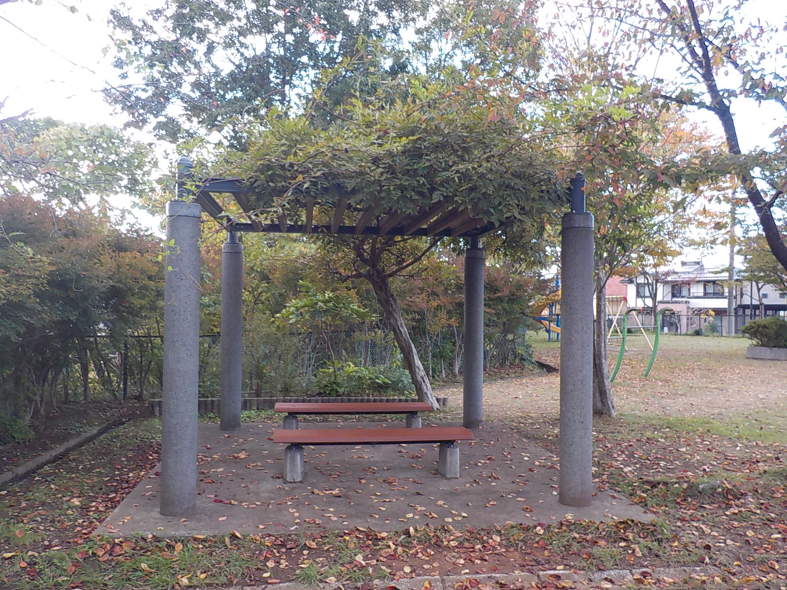 写真：公園内のパーゴラ。その下には2つのベンチが向かい合って設置されています