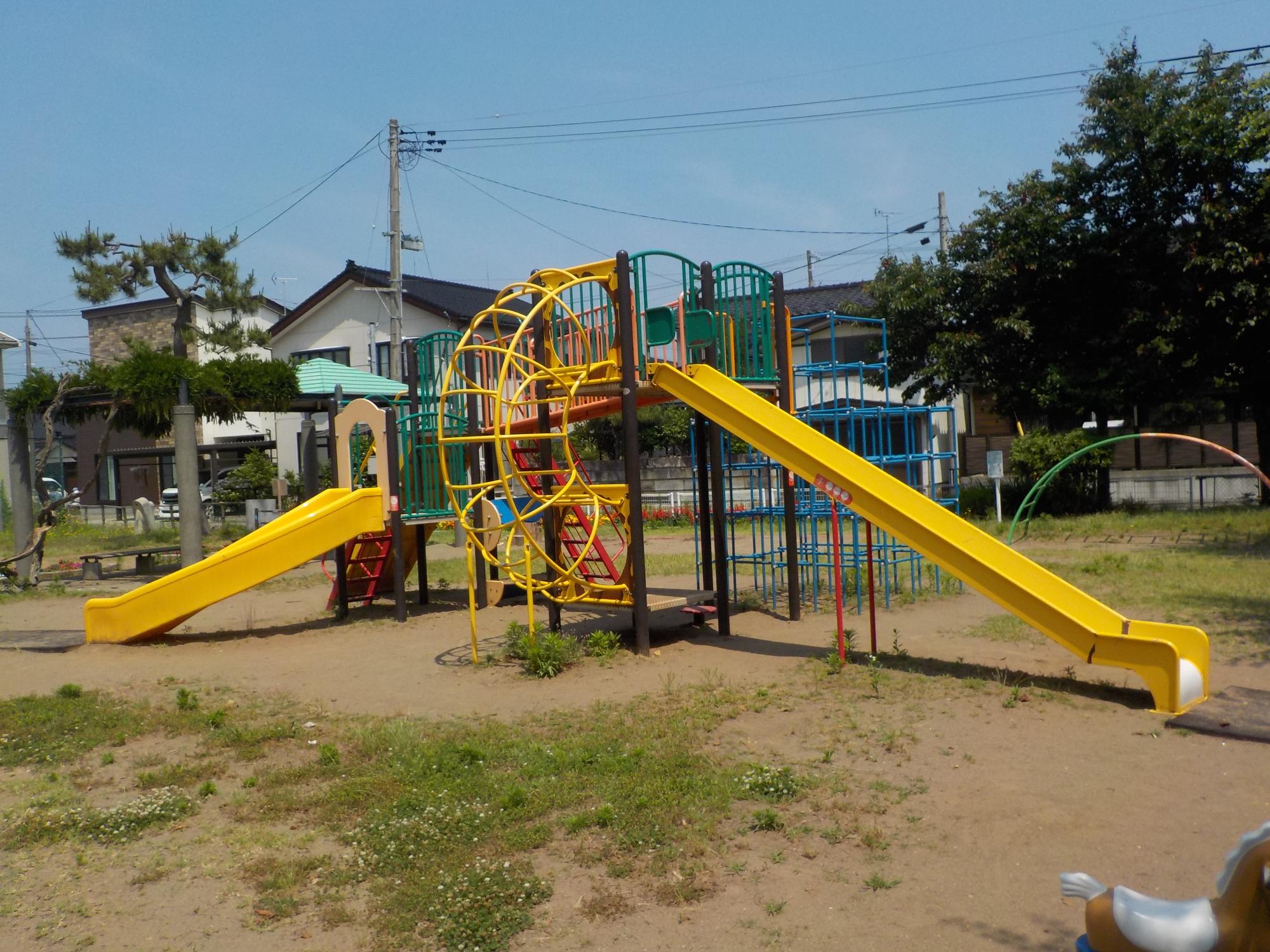 写真：大小の滑り台とラダーなどが組み合わさった大型複合遊具。奥にジャングルジムとうんていもあります