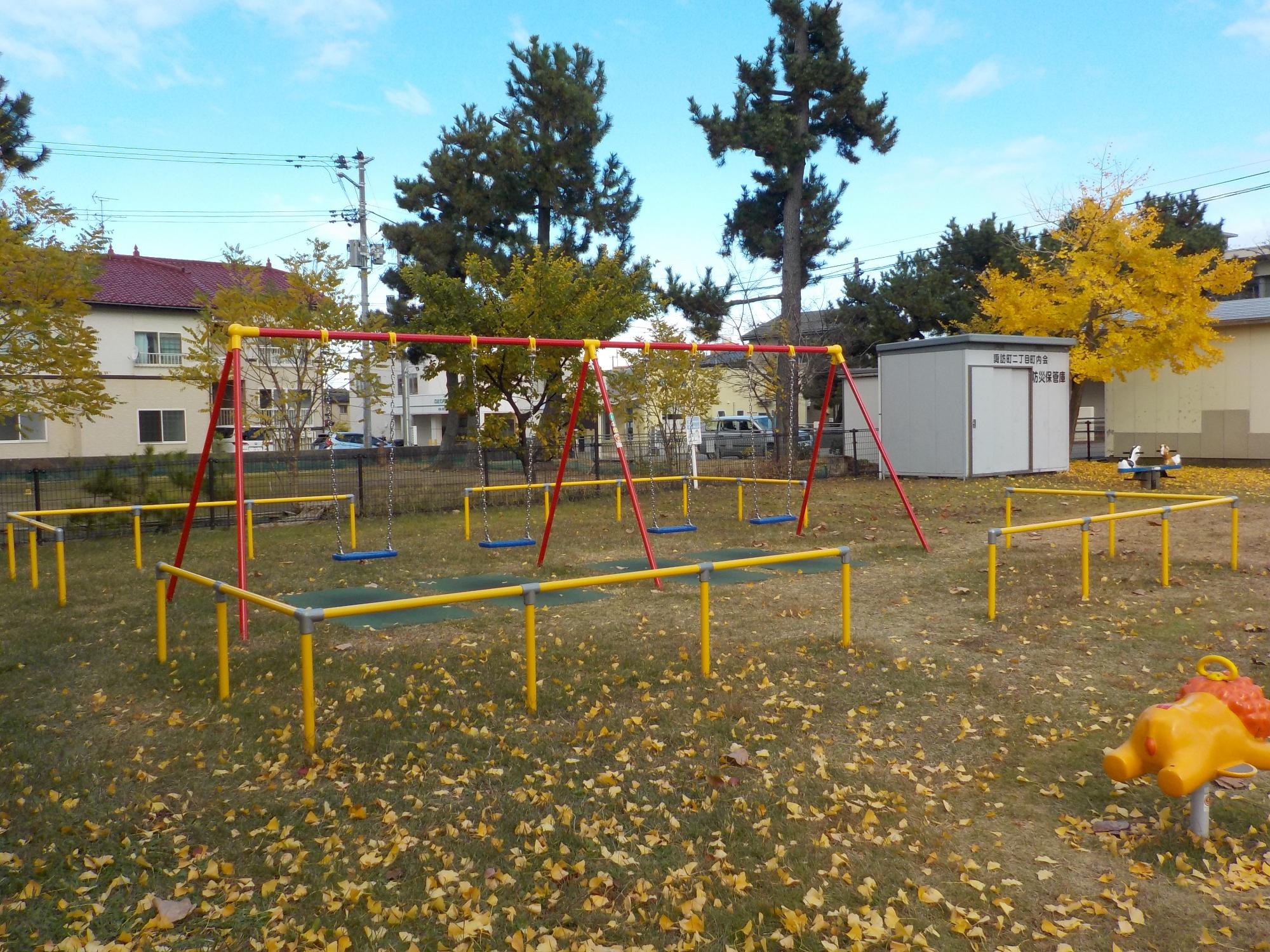 写真：4連ブランコがあり、周囲を囲むように柵があります。