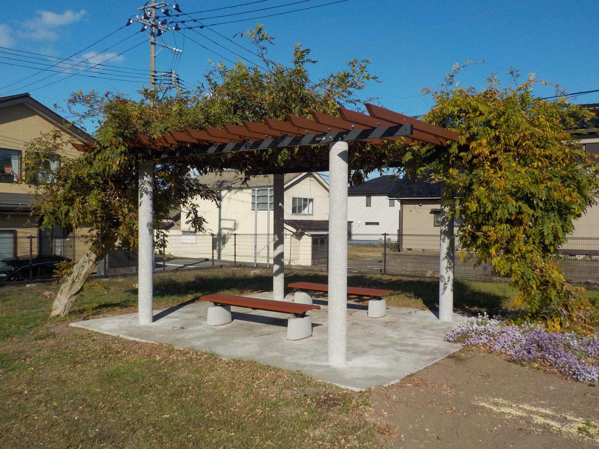 写真：植物が屋根代わりになるパーゴラの下にベンチが向かい合わせに設置されています