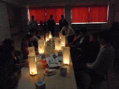 部屋を暗くして作った行灯に灯った明かりを楽しむ参加者の写真