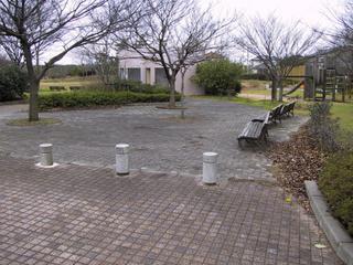 入口のインターロッキングの広場に木々が植えられていてベンチが並んで置いてある写真