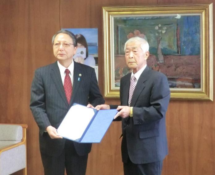 審査結果報告書を佐藤 俊雄委員長と市長が一緒に持って記念撮影している写真