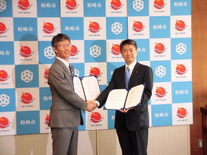 櫻井市長と北陸ガス株式会社の敦井社長がお互い引継書を持って握手している写真