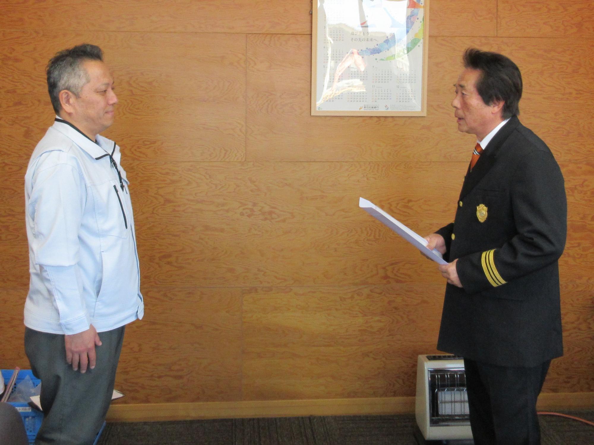 写真：田村柏崎市消防団長（写真右）が丸高建設株式会社の高橋代表取締役（写真左）へ感謝の意を伝えている様子