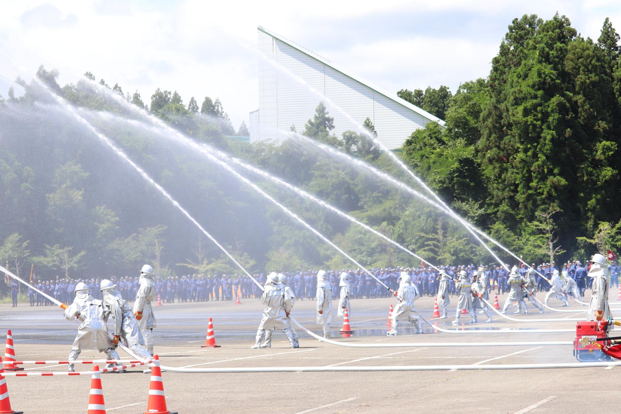 写真：消防団員が6隊に分かれ上空めがけて放水をしている様子