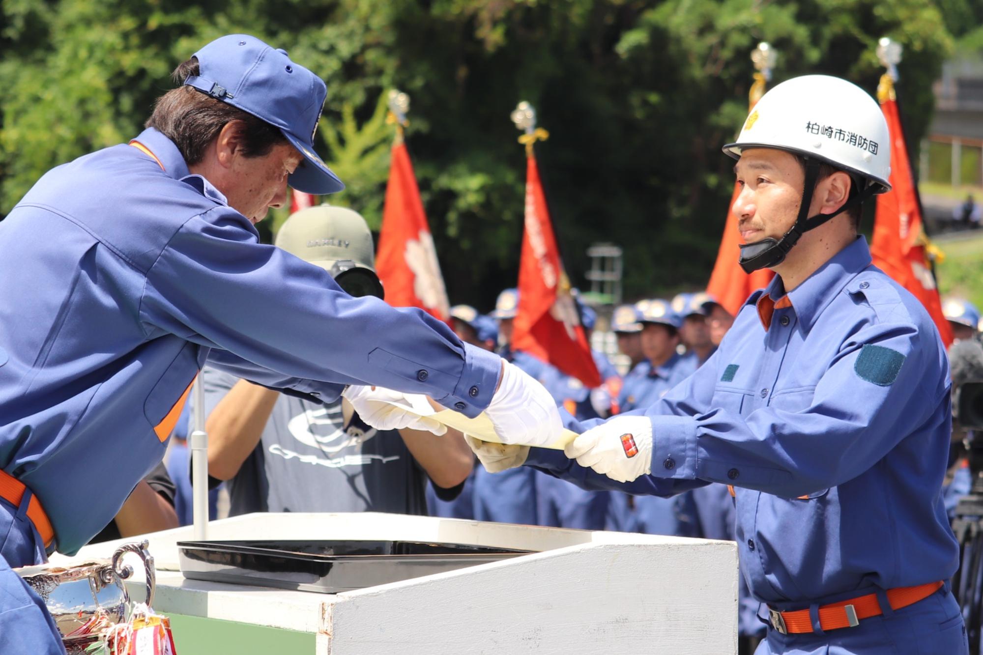 写真：田村地区支会長から賞状を受け取るポンプ操法選手