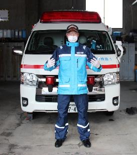 救急車の前で感染防止衣を着た男性救急隊員が正面を向いて立っている写真