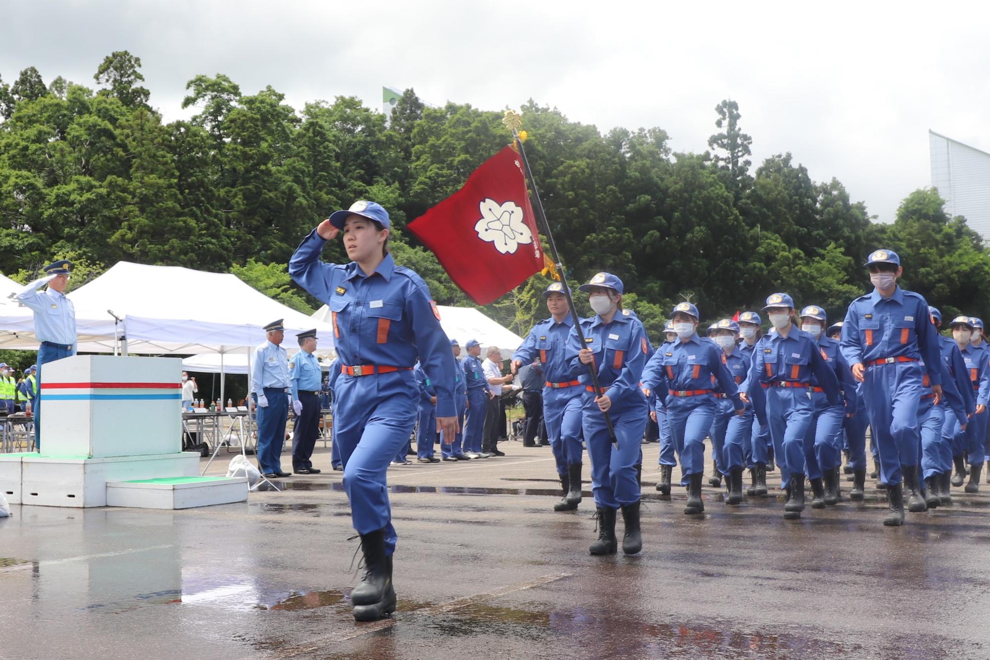 写真：市長へ敬礼を行う学生消防隊長を先頭に、分列行進を行う学生消防隊