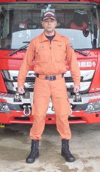 救助工作車の前にオレンジ色の救助服を着た救助隊員が立っている写真