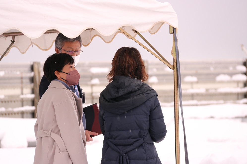 写真：小雪まじりの中、桜井市長の案内で中央海岸を視察するブヨン・リー一等書記官と東方麻由子政務補佐官