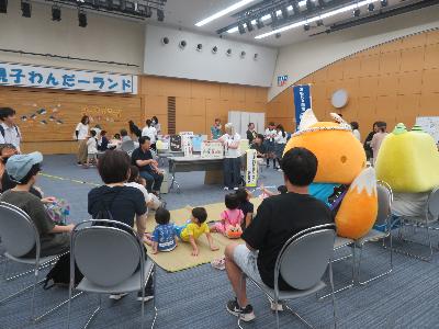 写真：絵本読み聞かせ(手話通訳付き) 親子がえちゴン、こーたんと一緒に絵本を読んでもらっています。