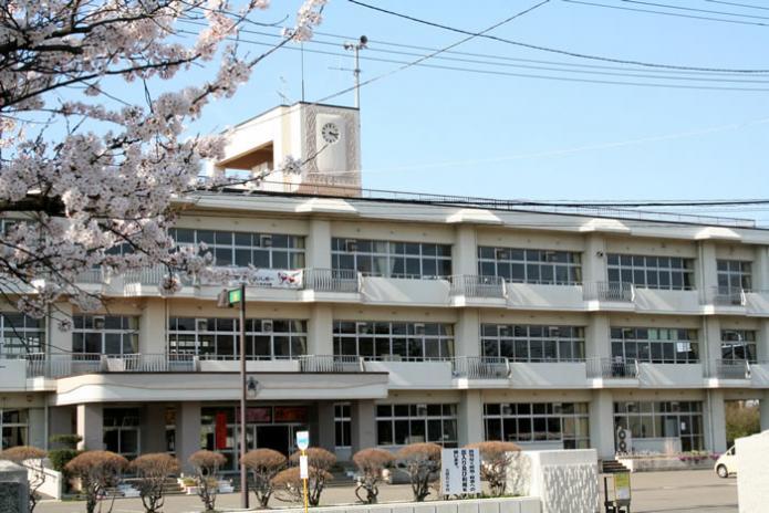 正門側から撮影された北鯖石小学校の校舎と手前に桜の枝が写っている写真