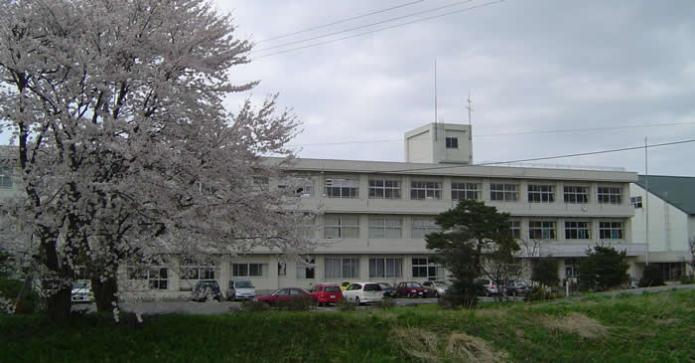 二田小学校の校舎の前の通りに開花している桜の木が写っている写真