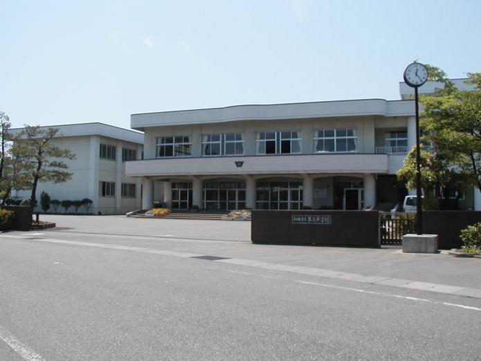 中学校正門の右横に背の高い時計があり、入口正面と左側に2階建ての校舎のある第三中学校の写真