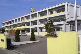 中学校の校門入口と校舎の一部の壁が淡い黄色で塗られている3階建ての瑞穂中学校の校舎の写真