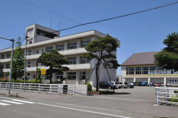 道路沿いに建っている南中学校の校舎と奥の体育館が写っている写真