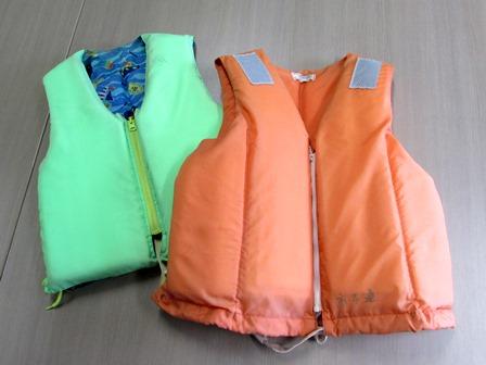 オレンジ色の大人用のライフジャケットと、表面が水色で、裏地が柄の入った青色の子ども用ライフジャケットの写真