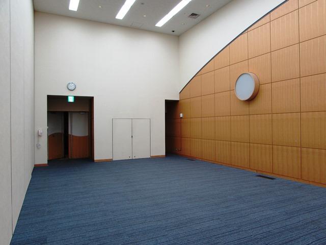 青いカーペットと白い壁に囲まれた、天井の高い部屋の写真