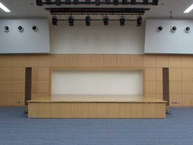 木目の壁の一部がステージになり、ステージが収まっていた部分の壁だけが白色になっている様子の写真