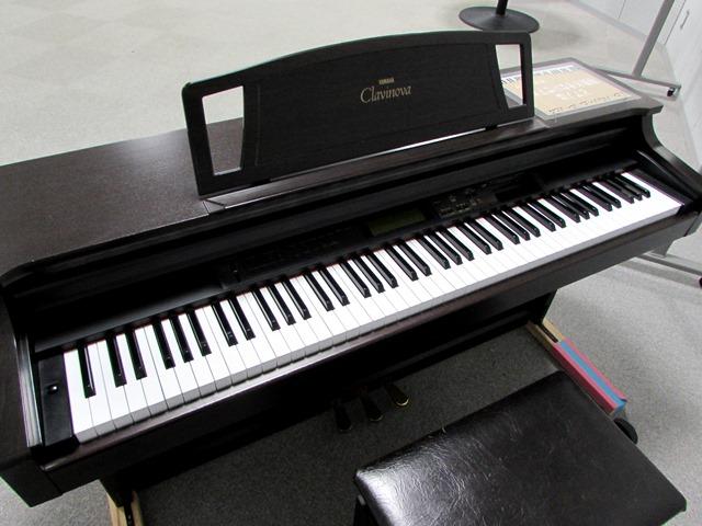 スタジオ101に置かれている白と黒の鍵盤が並ぶ、暗いブラウンの木目の電子ピアノの写真