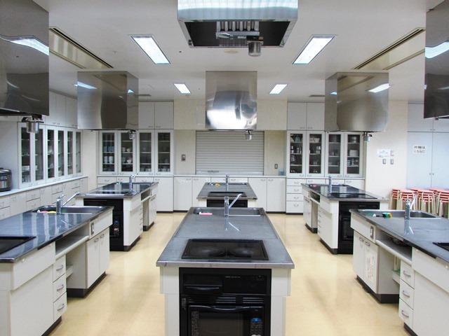 部屋の前と後ろに、それぞれ3台の調理台が並ぶ料理実習室の写真