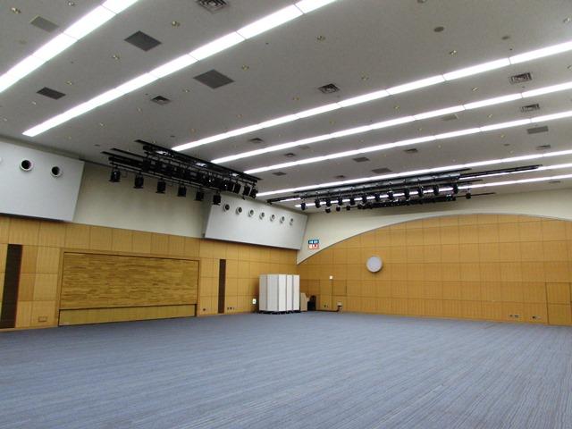 天井が高く、床に青いカーペットの敷かれたホールの写真
