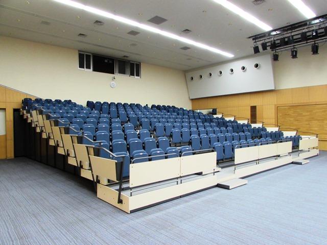 座面部分を手前に倒して座る青色の簡素な椅子が、ひな壇上状に並んでいる観覧席を設置した状態の写真
