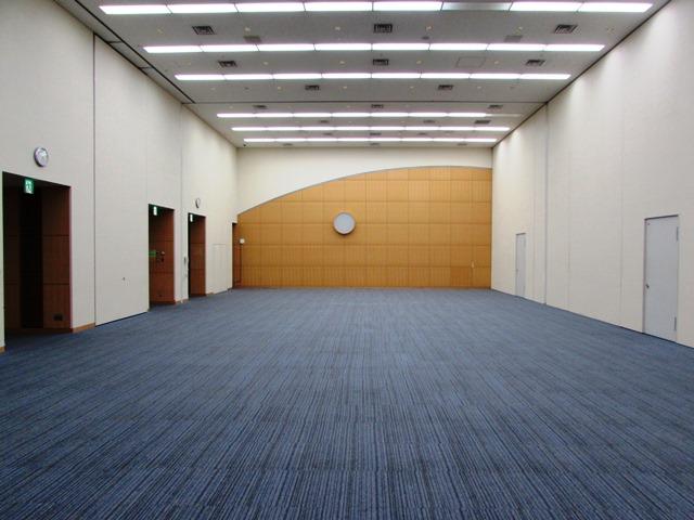 天井の高く、青色のカーペットが敷かれているホールの写真