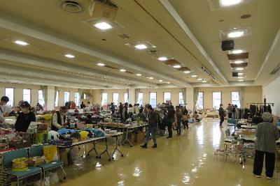 写真：3階大ホールで行われた前回のフリーマーケット。お客さんがお目当てのものを探しに各ブースを回っています。