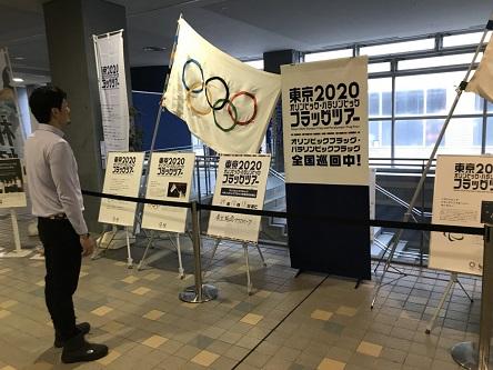 東京2020フラッグツアーのアクアパークでの展示品を白い服を着た男性が見つめている写真