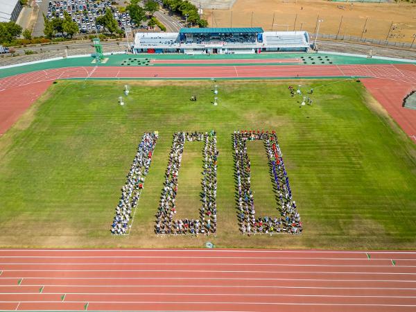 写真：柏崎市陸上競技場100周年記念式典の人文字の様子で参加者が100の文字を表現しています