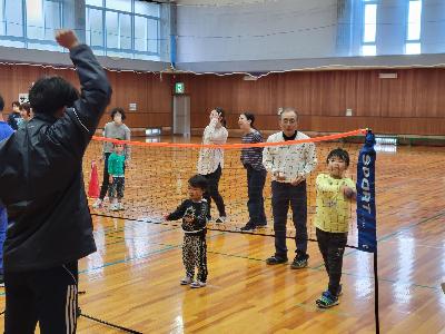 写真：指導者が投げるボールを、ネットの向こう側にいる子どもがキャッチしようとしています。