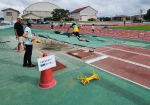 写真：陸上競技の参加者が幅跳びをしている様子。勢いよく跳んでいます。