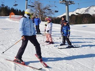 写真：指導員がスキーをはの字にして、参加者に止まり方を教えている様子