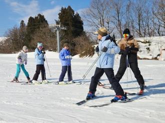 写真：スキースクールの指導者が参加者列の先頭で滑り方の指導をしています