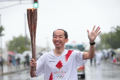 沿道に手を振りながら走る第2走者の佐藤明弘さん