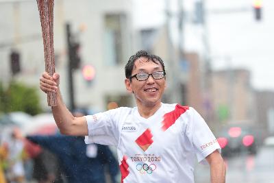 トーチの手を高く上げ走る第4走者の津吉秀樹さん