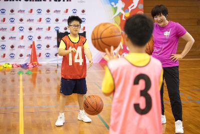 写真：『バスケットボール】子どもたちが向かい合ってボールパスをしています。講師が横で見守っています。