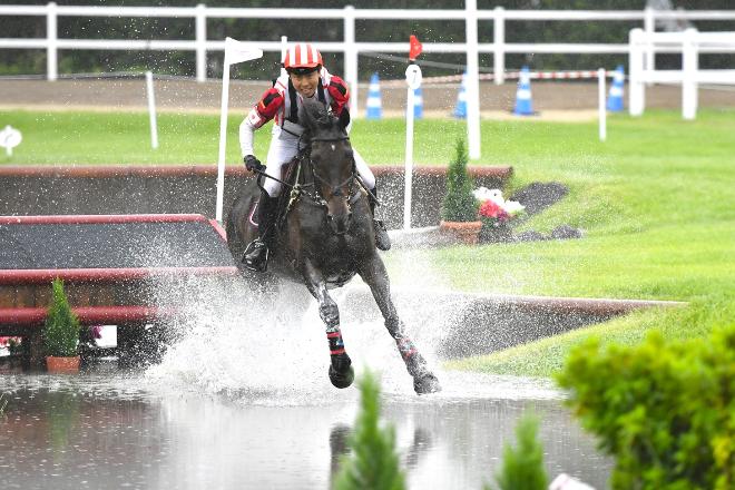 写真：水しぶきをあげながら水ごう障がいを飛越する村田選手とヴィケンティ号
