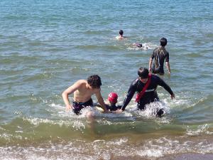 写真：海で大会に向けた練習をしています。男性2人がペアを組んでマネキンを救助しています