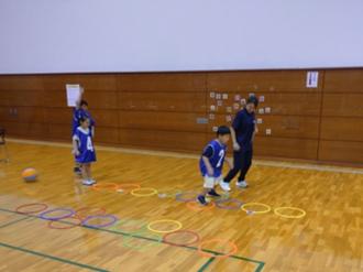 写真：床に並んだ輪を、引いた数字の数だけけんけんぱ運動をするお子さん