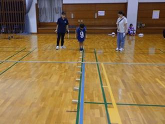 写真：参加者が床に置かれた積み木を踏まないように、連続で跳ぼうとする様子