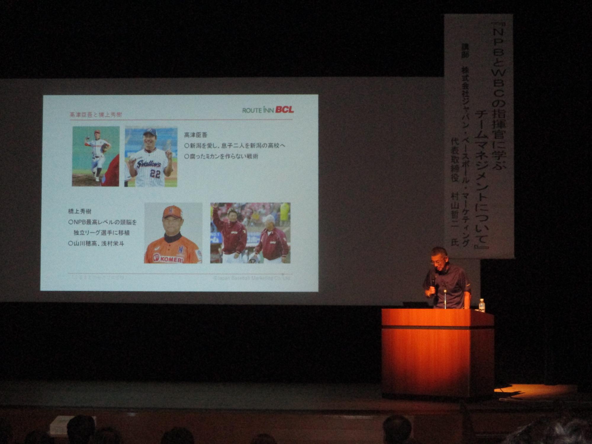 写真：野球選手の写真をスライドに映しながら、村山哲二さんがスポーツの内容を中心に講演をしている様子です