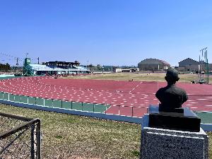 写真：陸上競技場に向かって建てられた坂田四郎吉像の後ろ姿の写真です