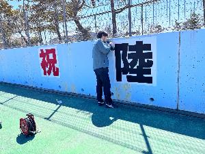 写真：陸上競技場のフェンスに記念パネルを取り付けている様子です