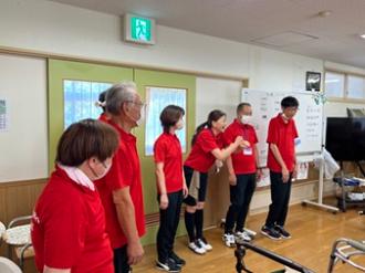 写真：スポーツ推進委員が5人並び、そのうちの一人が手話を交えながら挨拶をする様子