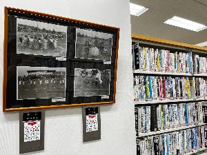 写真：図書館で開催されている図書間ミニ展示の様子で競技場建設初期頃に開催されていた大会の写真が飾られています