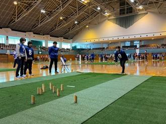 写真：男性が狙いを定めてモルックを投げた様子です